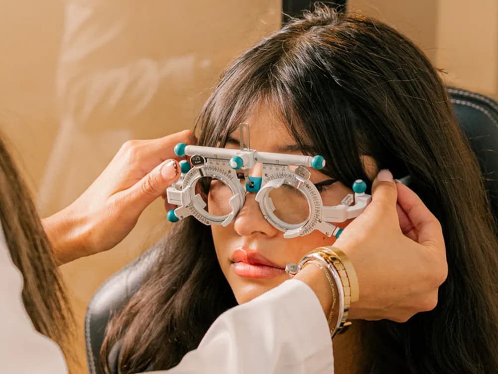 Optometrista ajustando una montura de prueba a una paciente durante el examen de la vista